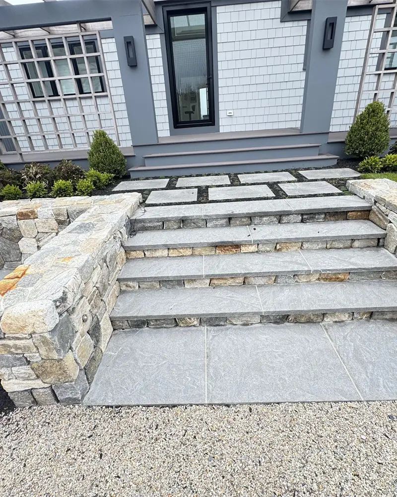 Bluestone patio with dry-laid stone steps and retaining walls built by Braun Construction on Cape Cod