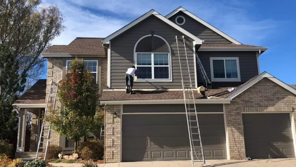 Braun Construction painter preparing exterior siding and trim for repainting on a Cape Cod home