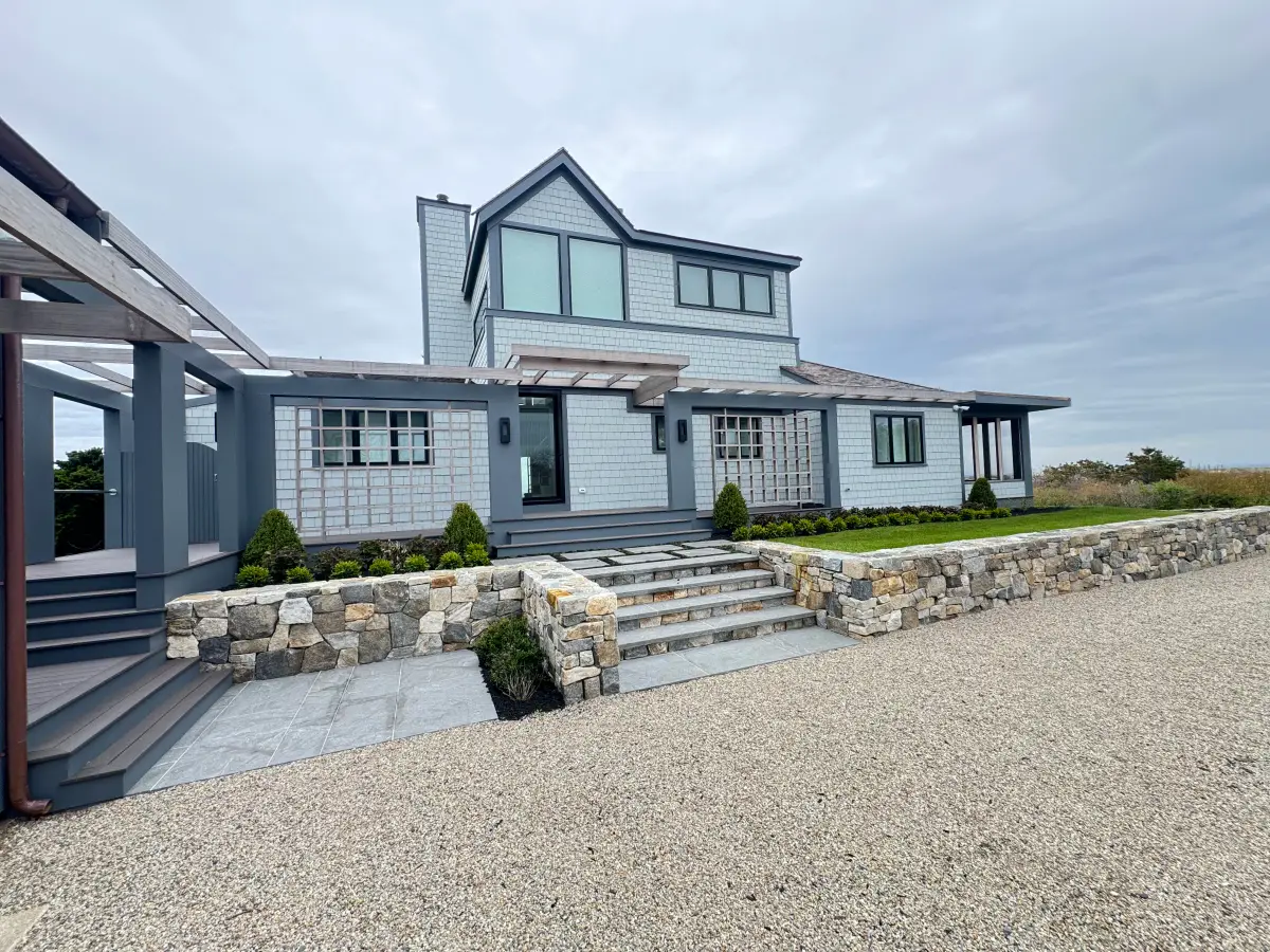 Fieldstone retaining wall and granite steps fronting a shingle-style coastal home built by Braun Construction on Cape Cod