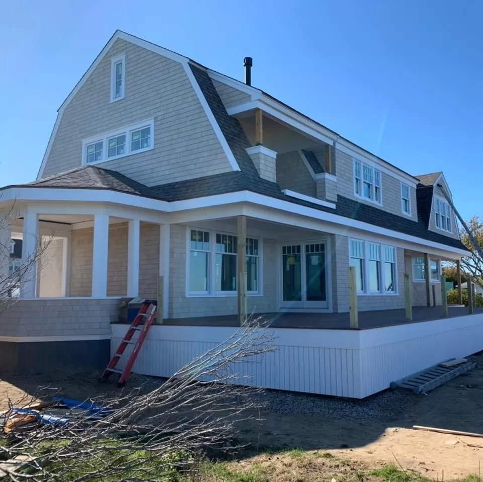 Gambrel roof with new architectural shingles on a shingle-style home with wraparound porch on Cape Cod
