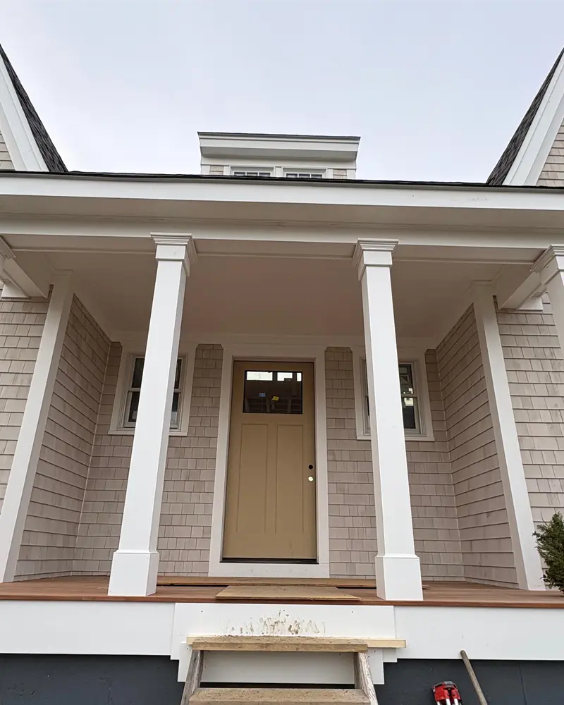 Crisp white porch columns, casings and fascia trim installed by Braun Construction on a Cape Cod home