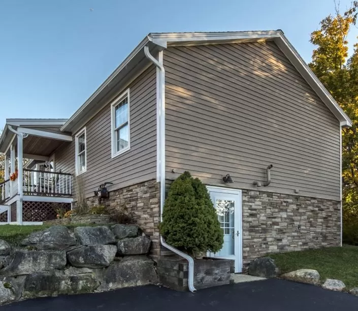 Vinyl siding with stone veneer accent on a New England home addition by Braun Construction